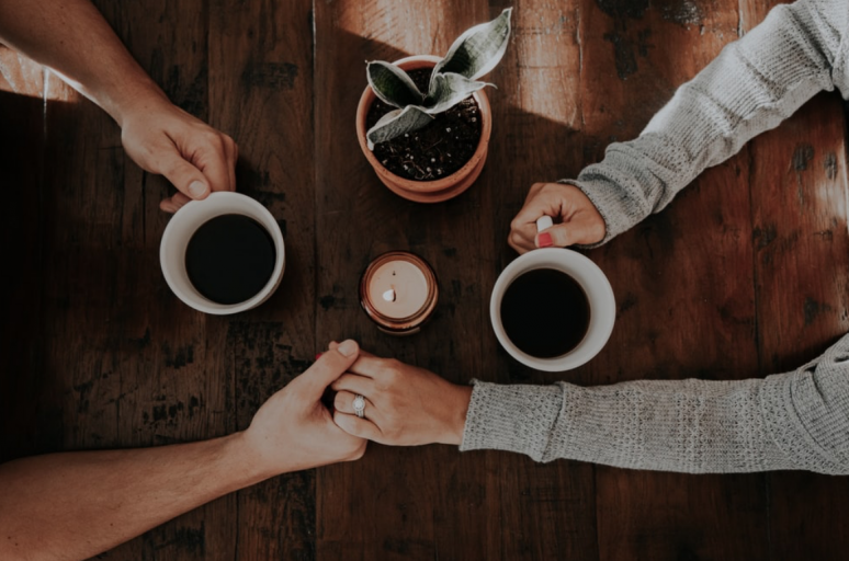 A couple holding hands while drinking coffee